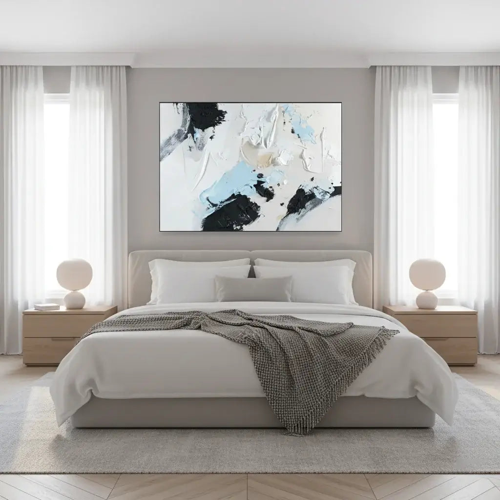 Modern bedroom with a bed, abstract art on the wall, and side tables with lamps.