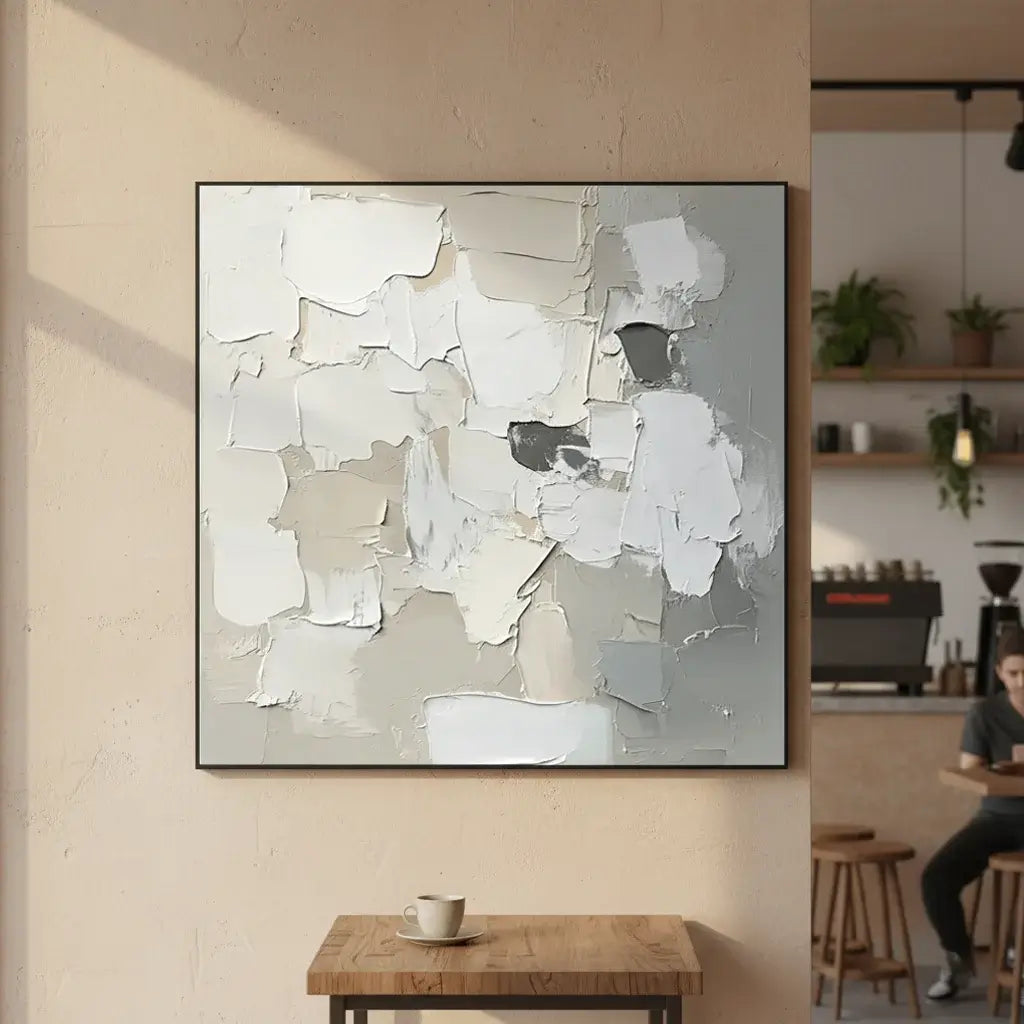 Abstract art piece on a wall in a room with a wooden table and person sitting.
