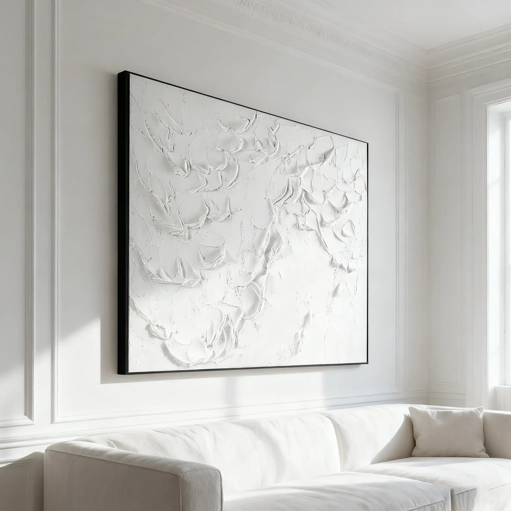 Abstract artwork in a black frame on a white wall above a sofa