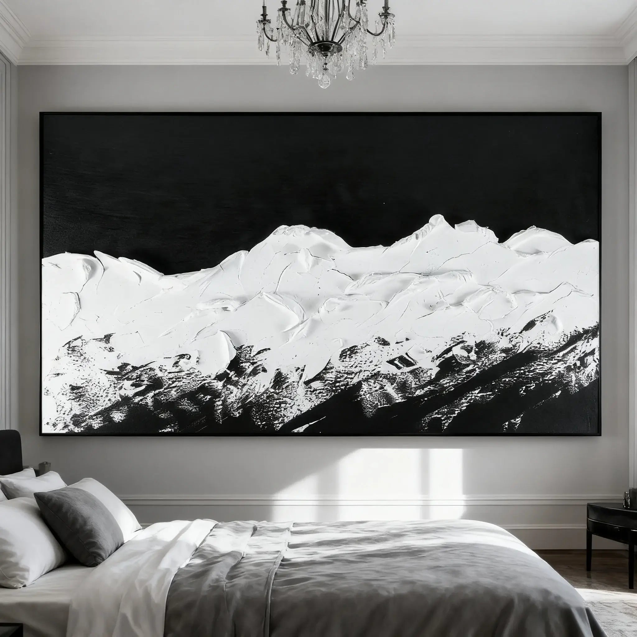 Large black and white mountain landscape painting in a bedroom with a bed and chandelier.