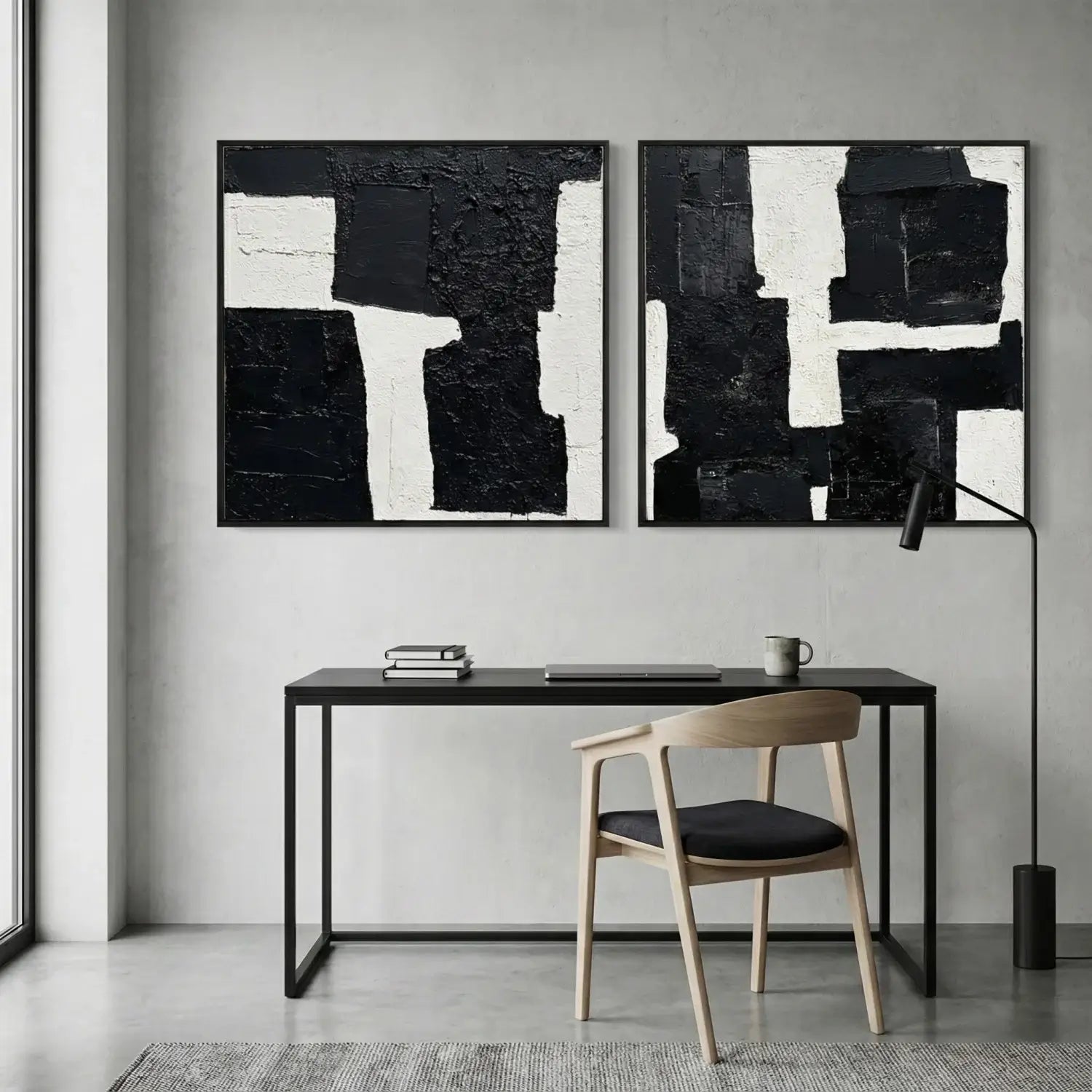 Modern office setup with abstract black and white paintings on the wall, a desk, and chair.