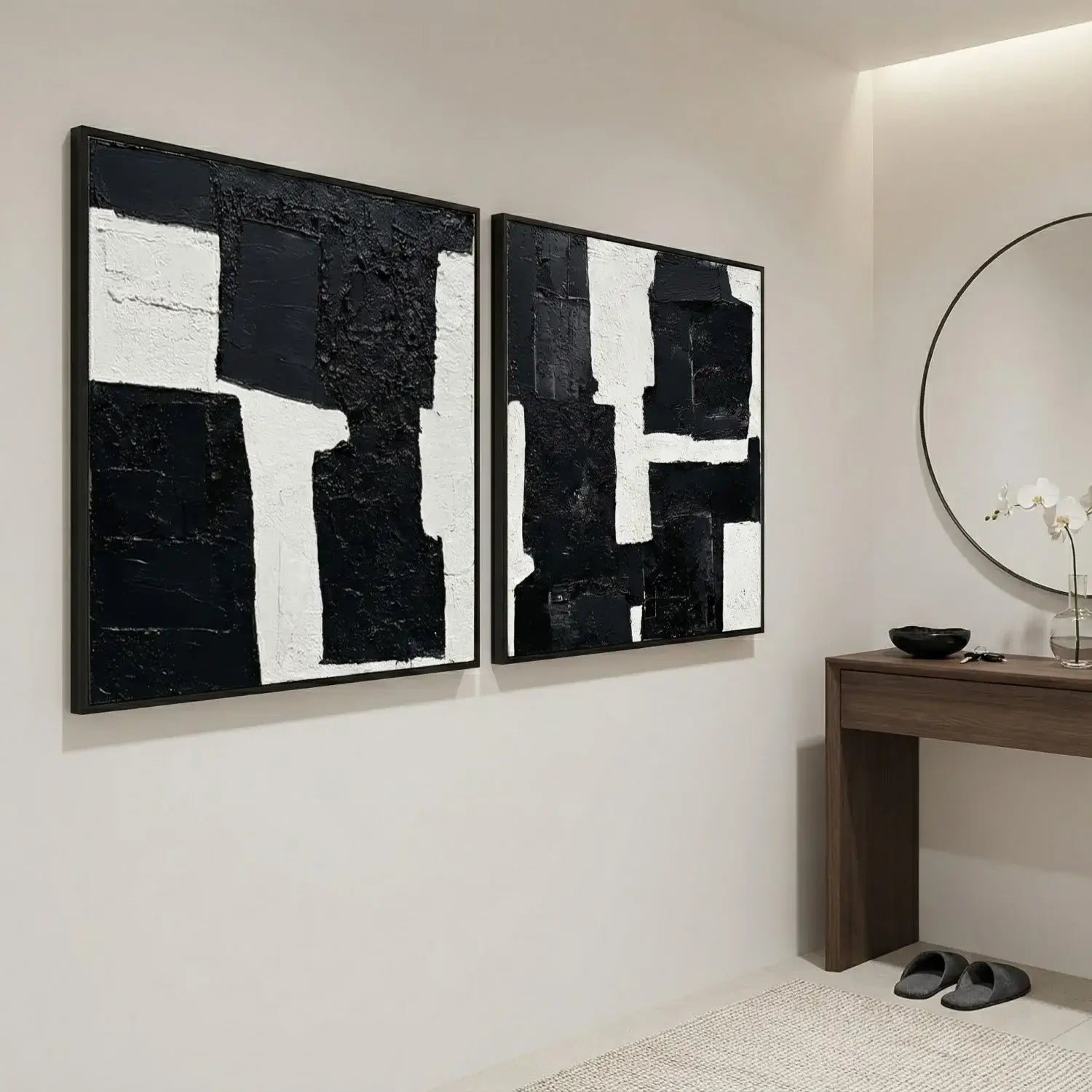 Two abstract black and white paintings on a wall in a modern interior setting.