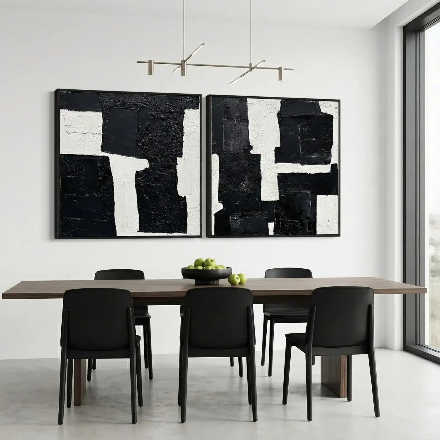 Dining room with a wooden table and black chairs, featuring two large abstract black and white paintings on the wall.