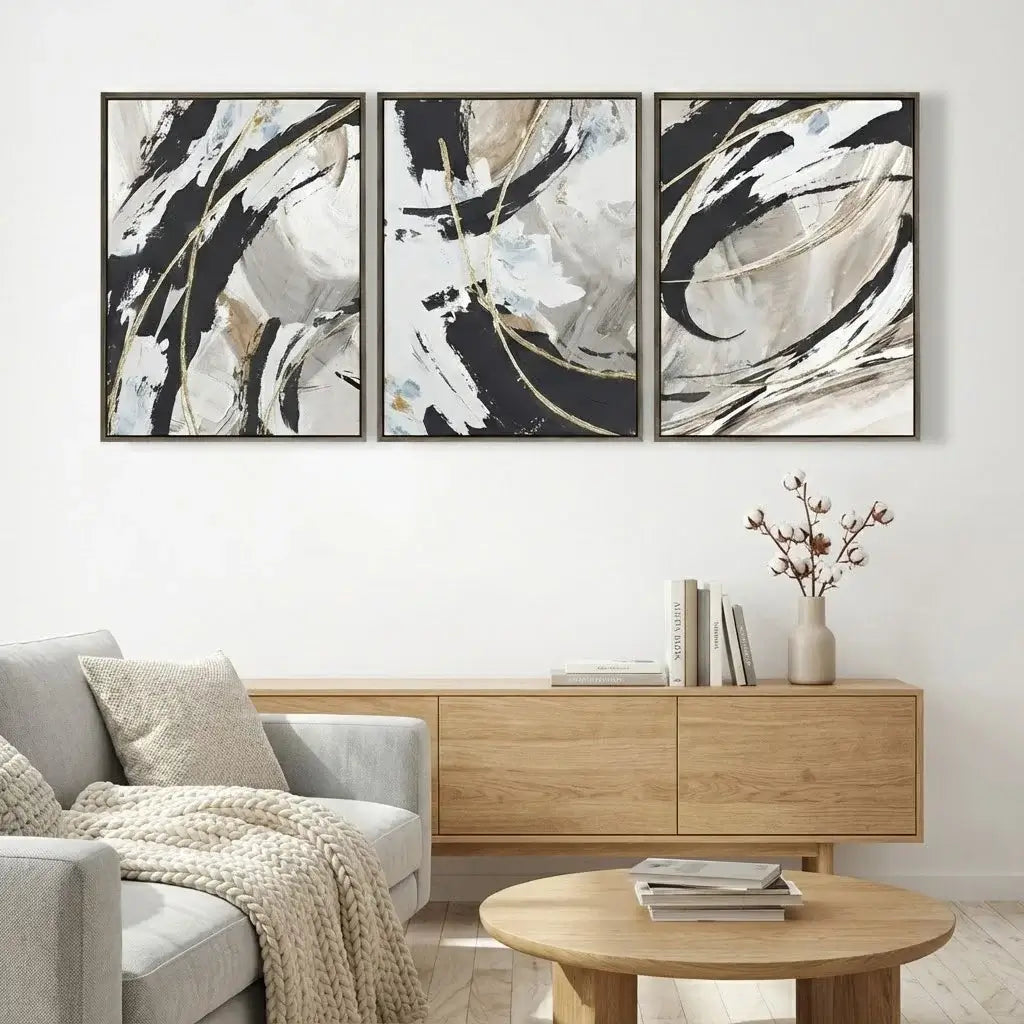 Three abstract paintings above a wooden console table in a living room.