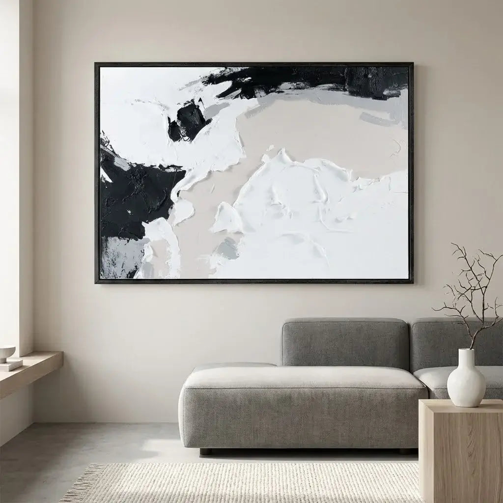Abstract black and white painting on a wall above a gray sofa in a living room.