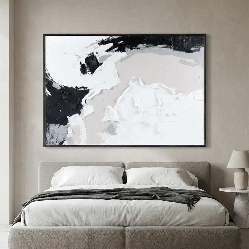 Abstract black and white painting above a bed in a bedroom setting
