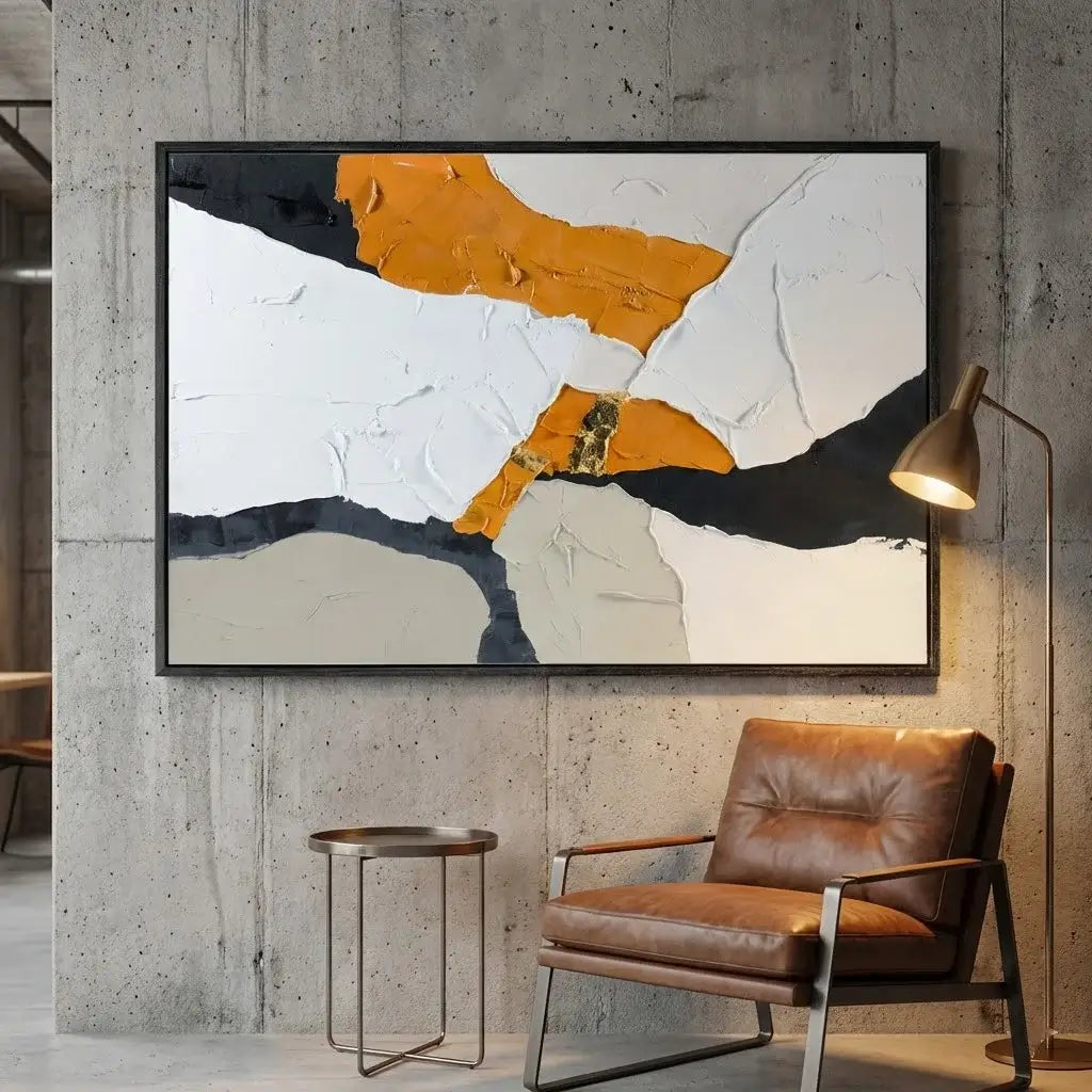 Abstract art piece on a concrete wall with a brown leather chair and side table.