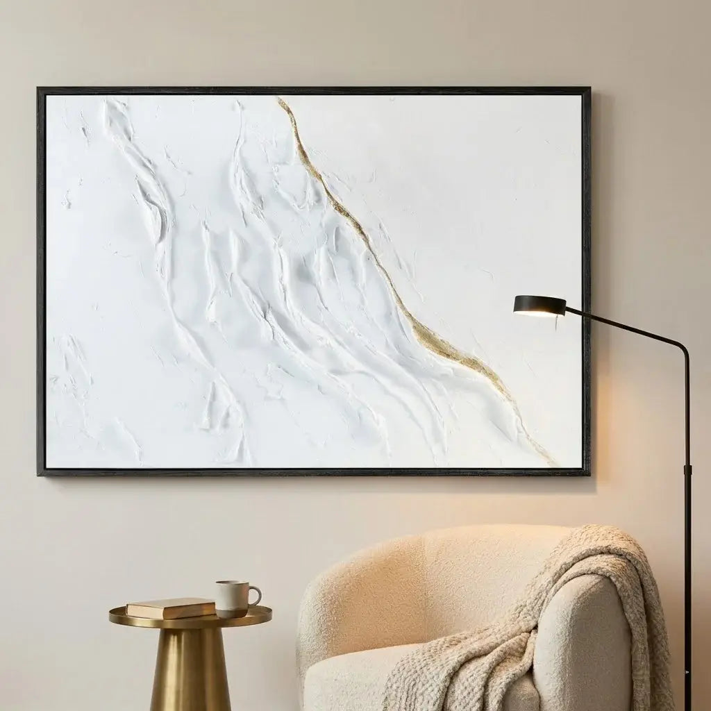 Framed abstract art piece on a wall above a chair with a side table.