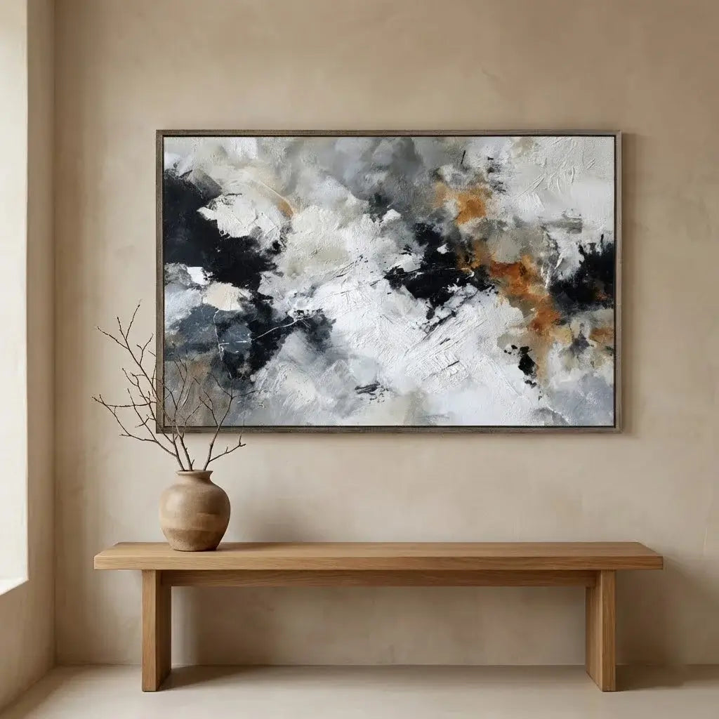 Abstract painting on a beige wall above a wooden bench with a vase containing branches.