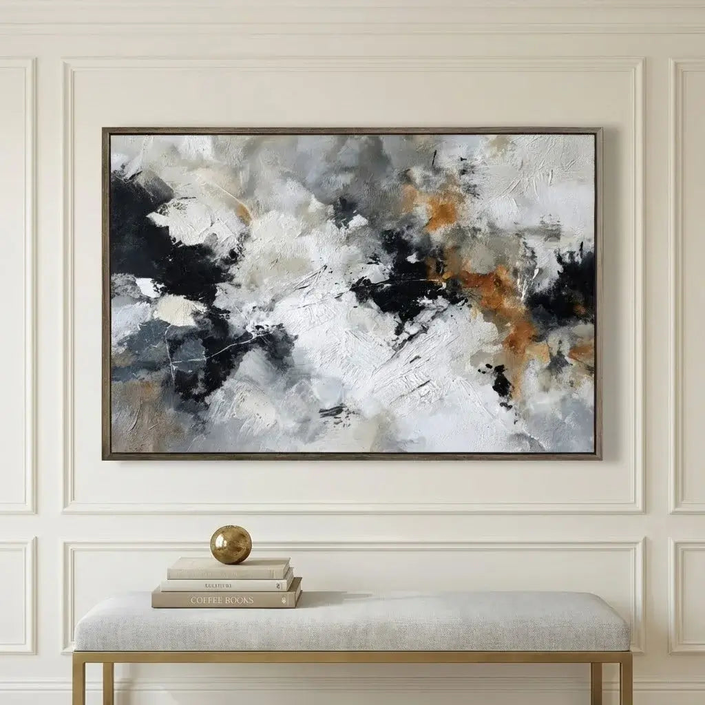 Abstract painting with black, white, and gold tones on a wall above a console table.