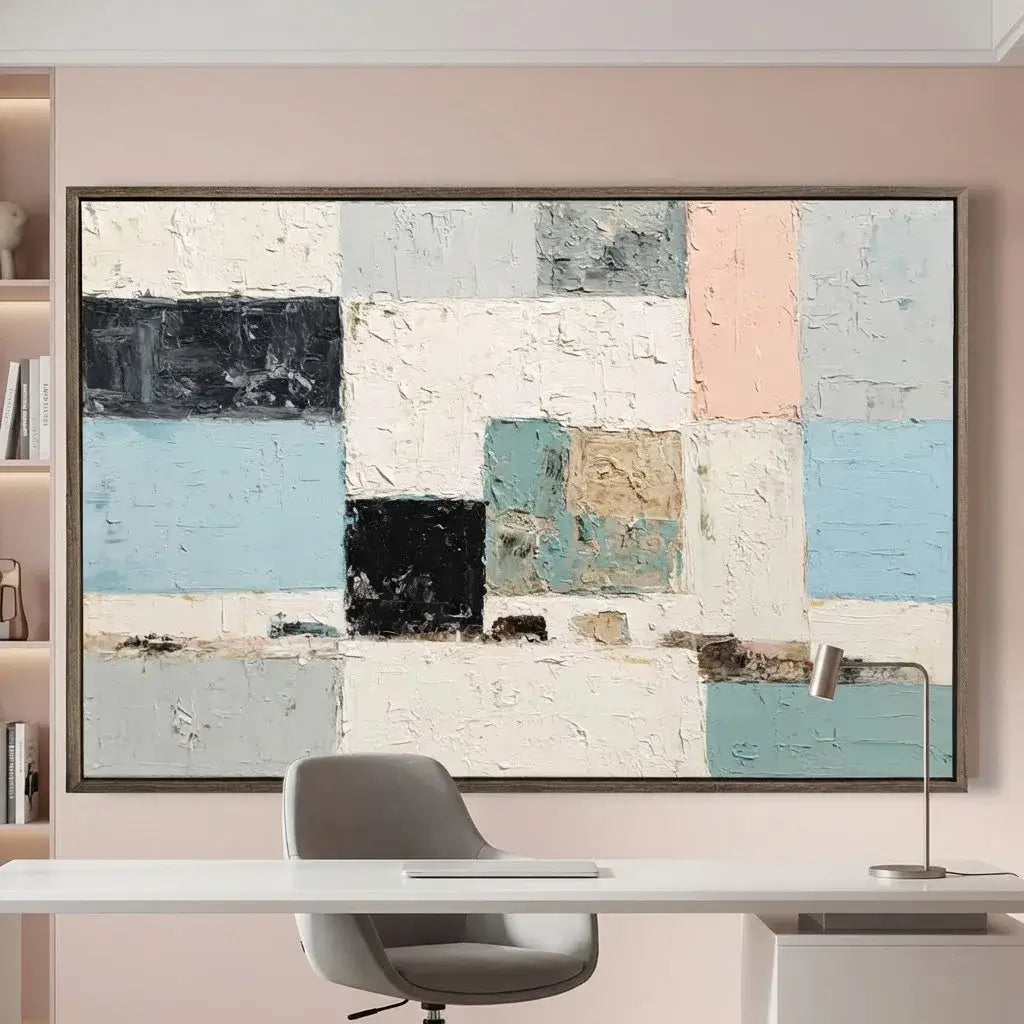 Abstract art piece on a wall above a desk with a chair.