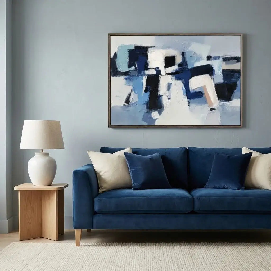 Modern living room with a blue sofa, abstract painting, and lamp.
