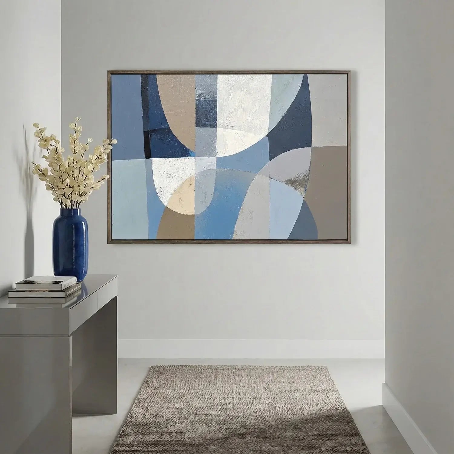 Abstract art piece on a wall with a vase and books on a console table.