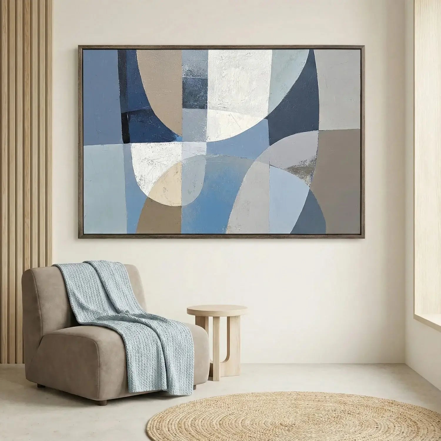 Abstract art piece on a wall above a chair with a blue blanket in a living room setting.