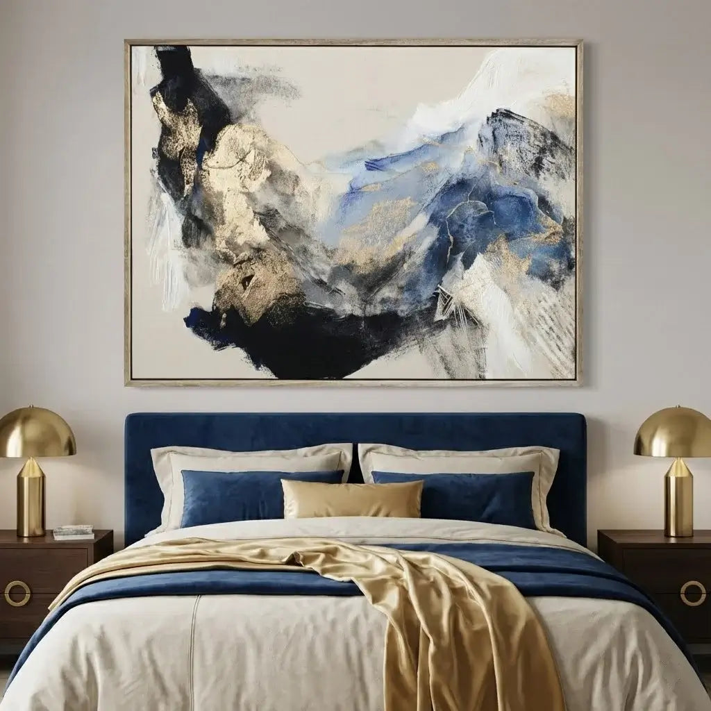 Modern bedroom with abstract art above a bed, gold lamps on nightstands, and blue and gold bedding.