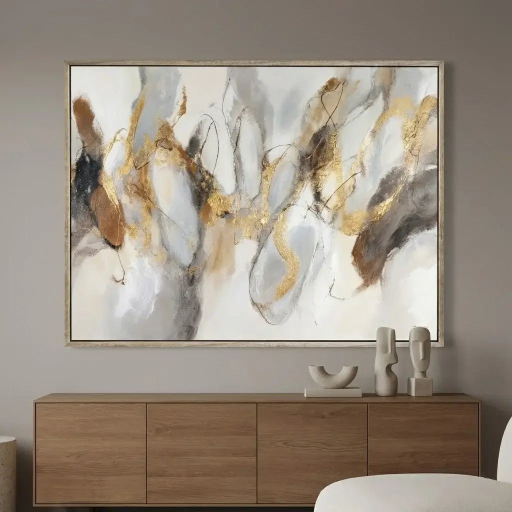 Abstract art piece with gold and brown accents on a wall above a wooden cabinet.