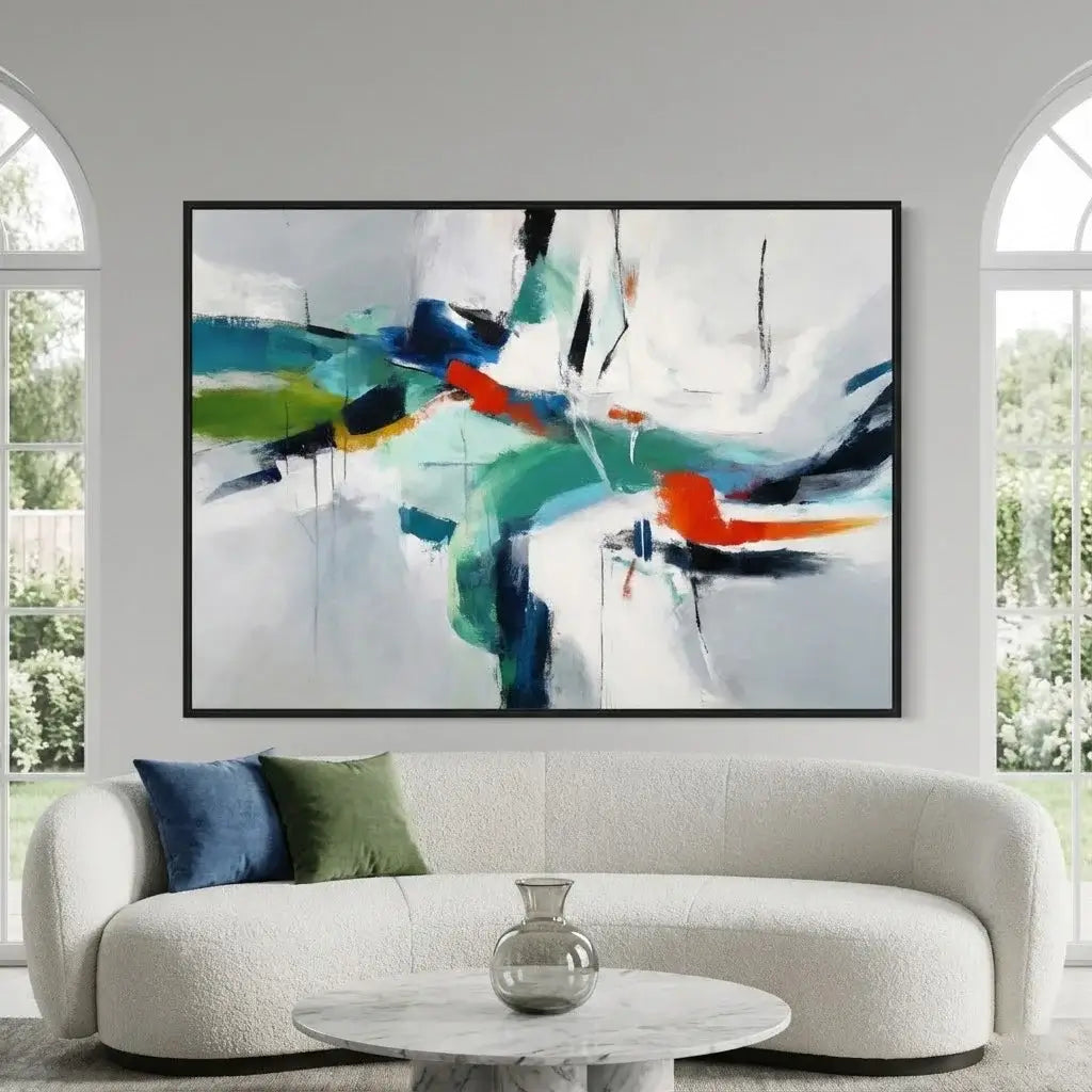 Abstract painting on a wall above a sofa with decorative pillows and a small table.