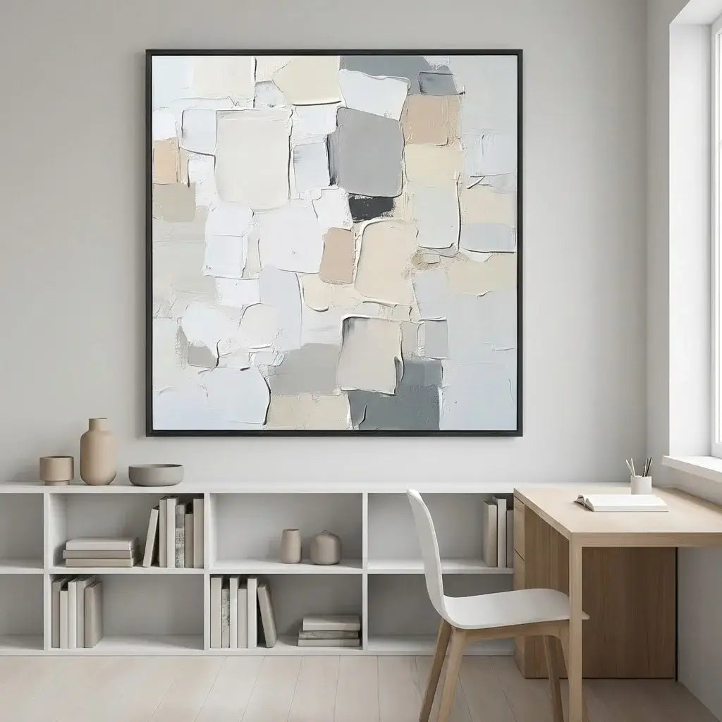 Abstract art piece on a wall above a desk and bookshelf in a room.