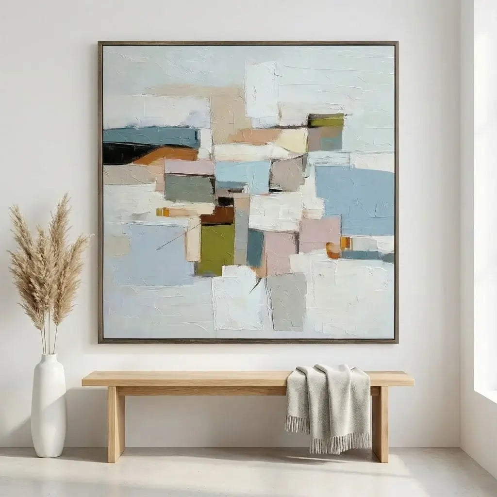 Abstract art piece on a wall above a wooden bench with a vase and blanket.