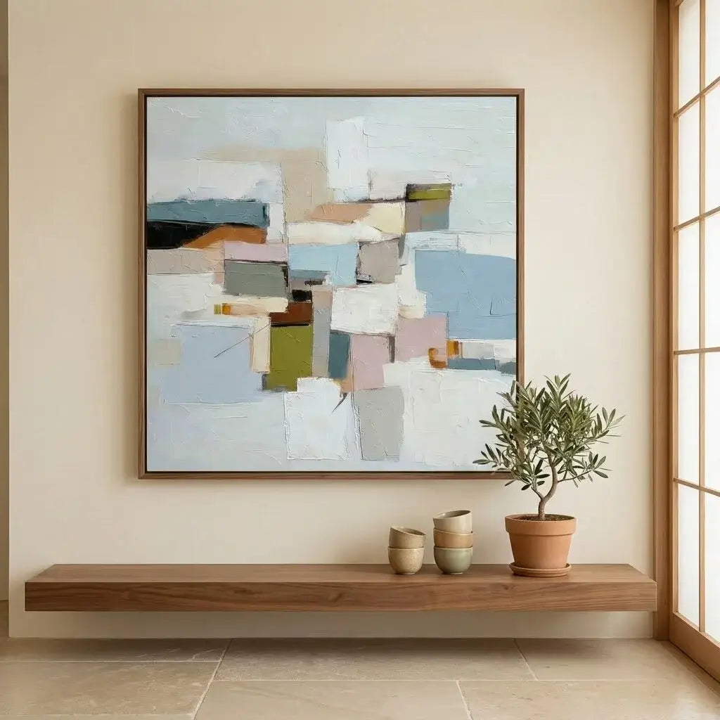 Abstract art piece on a wall above a wooden shelf with decorative items.