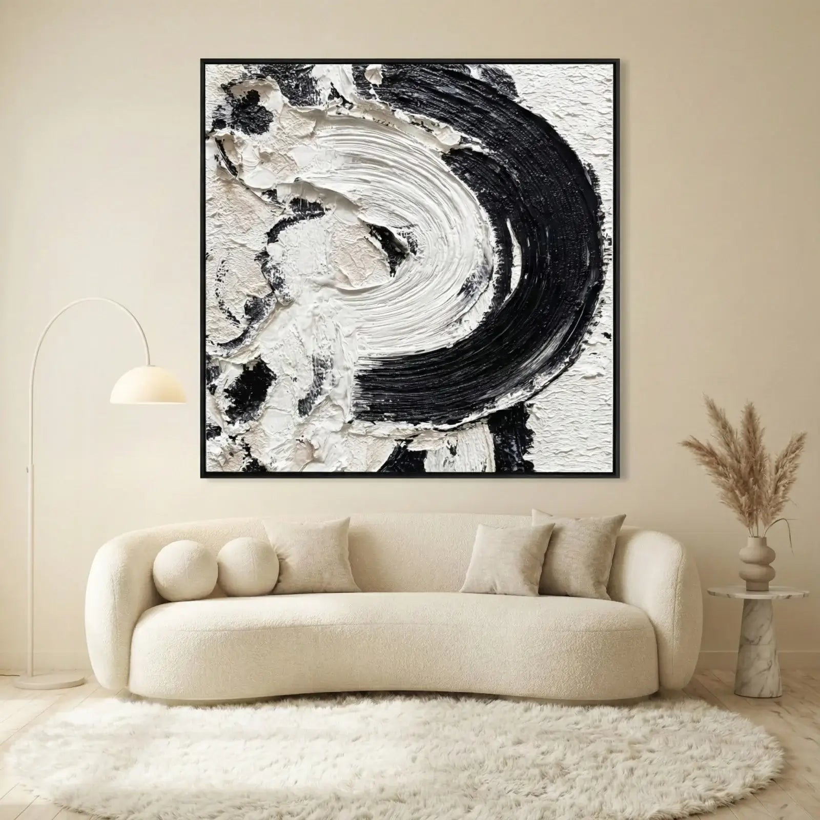 Abstract black and white painting on a wall above a beige sofa in a living room.