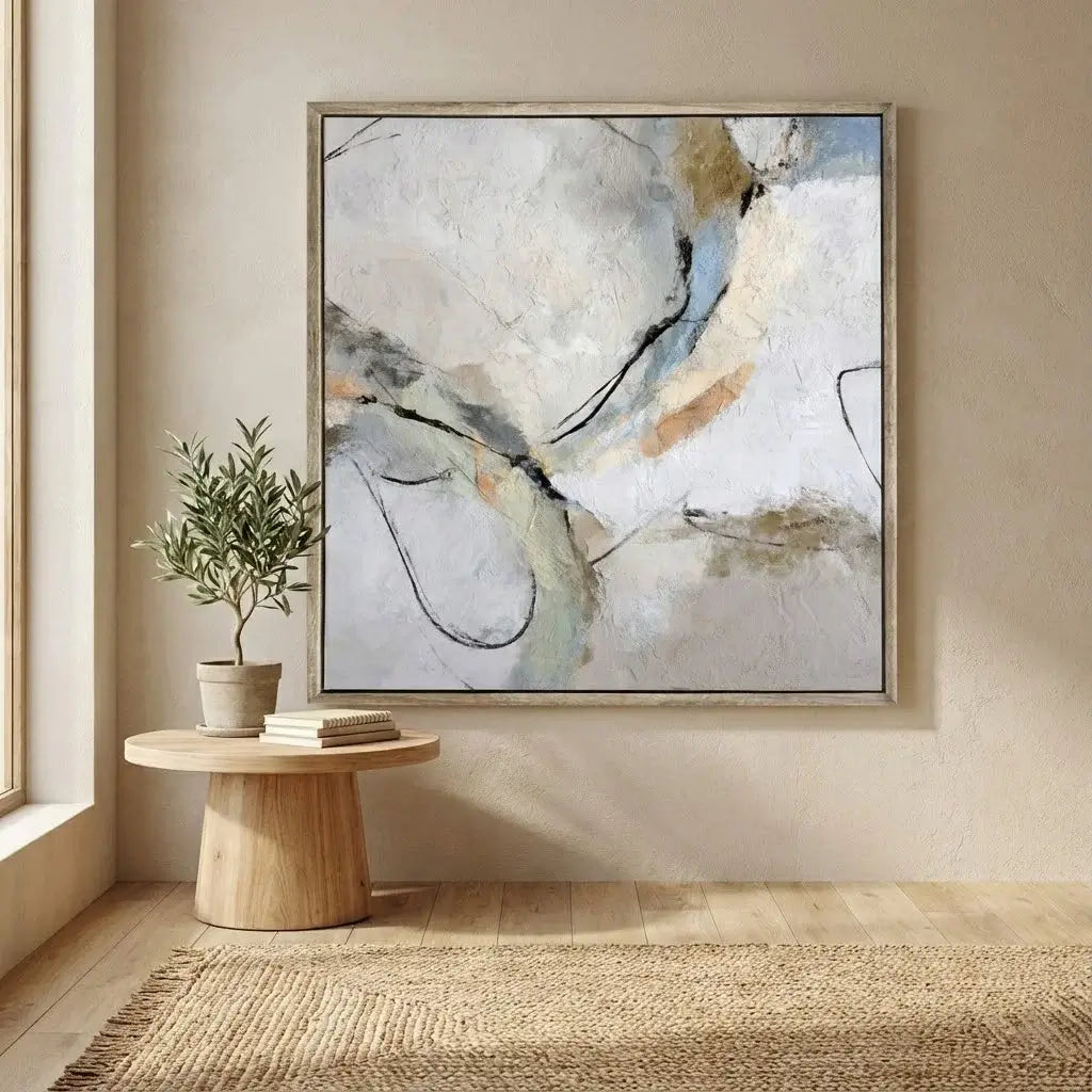 Abstract painting on a wall above a wooden table with a plant in a minimalistic room.