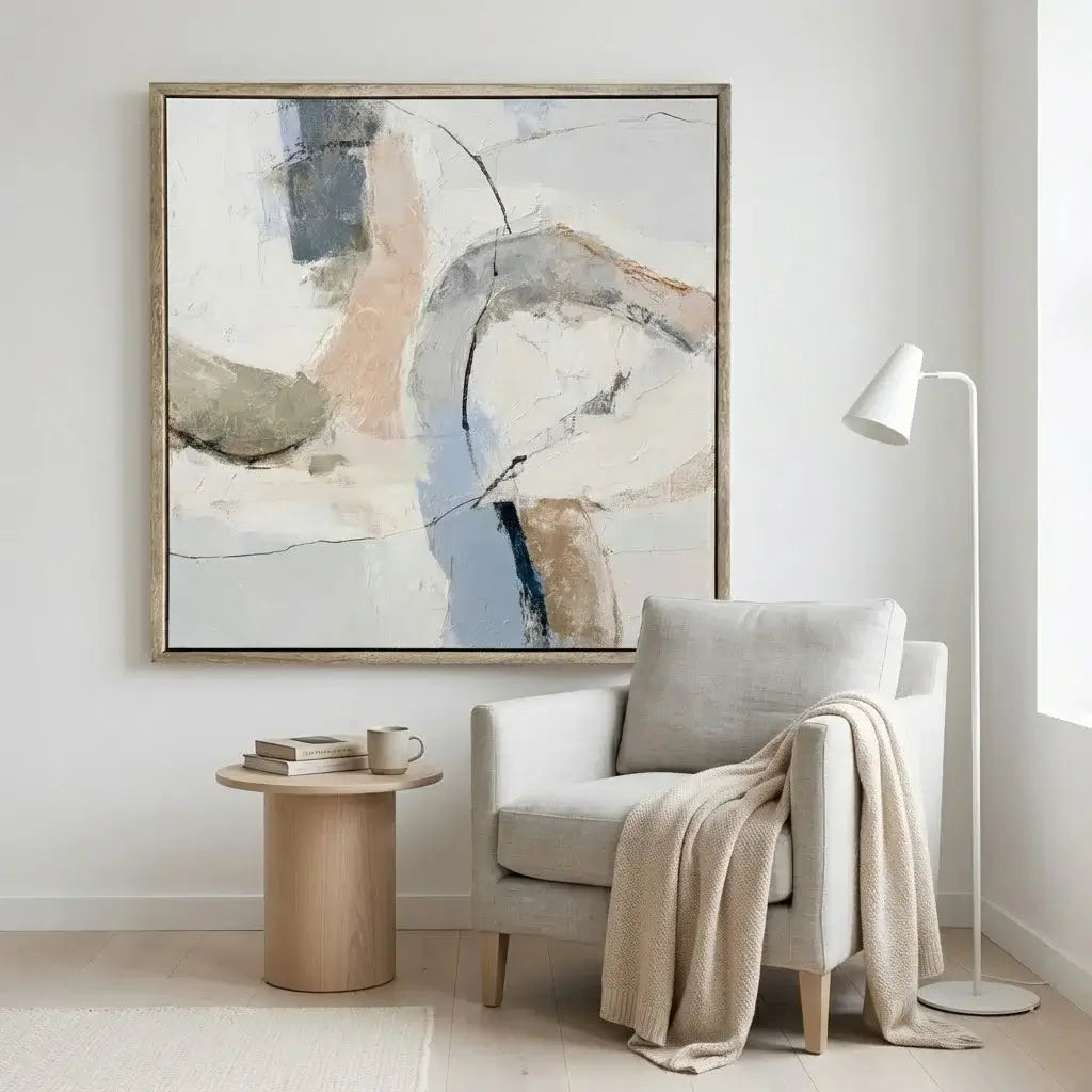 Modern living room with a gray armchair, abstract painting, and side table.