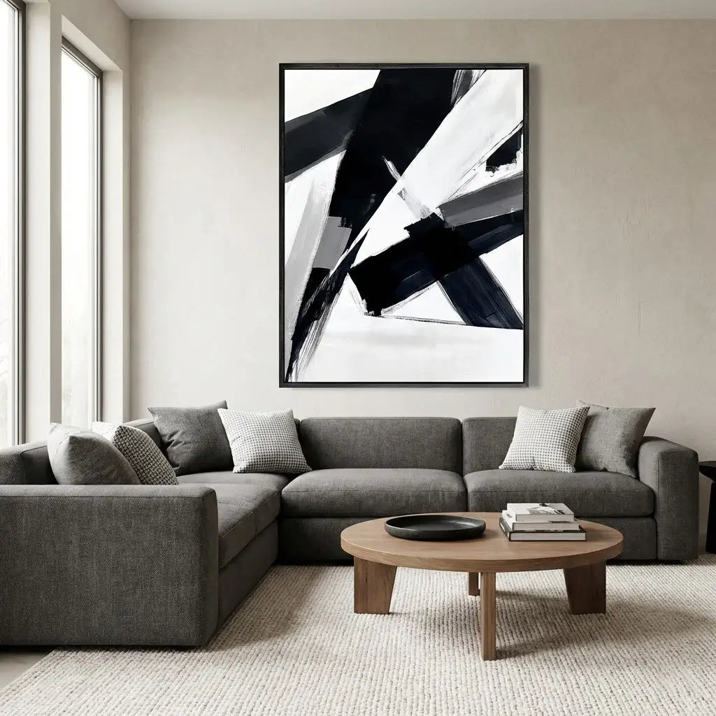 Modern living room with a gray sectional sofa, round wooden coffee table, and abstract art on the wall.