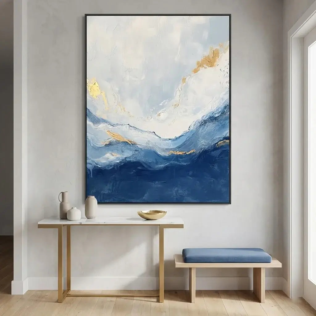 Abstract painting with blue and gold tones on a wall above a console table and bench.
