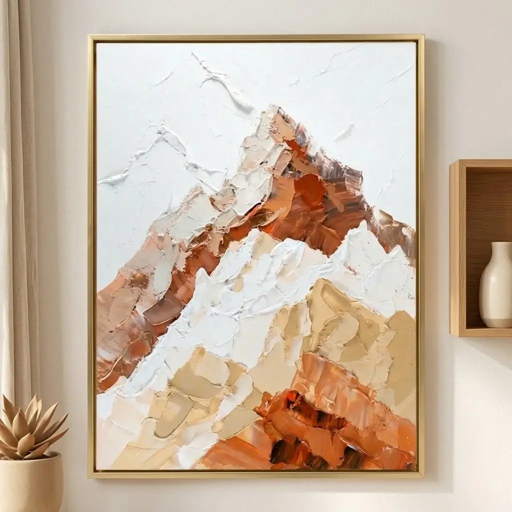 Framed abstract mountain art above a wooden desk with a lamp and plant.