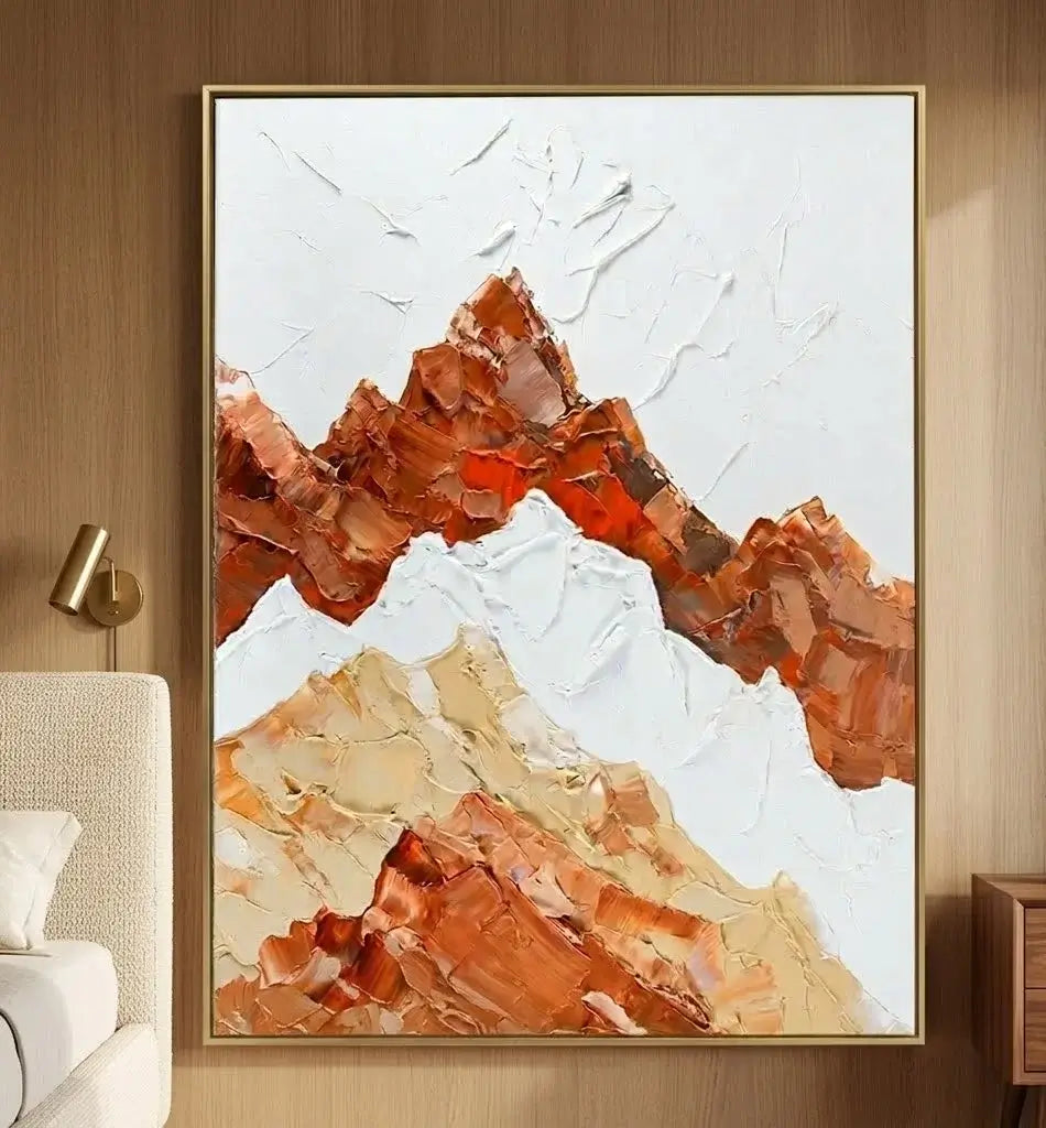 Framed abstract mountain art piece on a wall above a desk with books and decor.