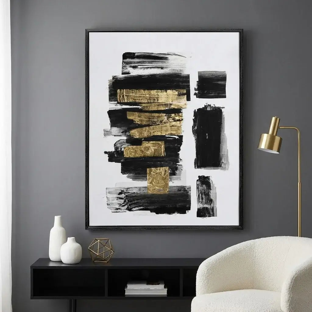Abstract art print with black and gold brush strokes on a gray wall above a black console table.