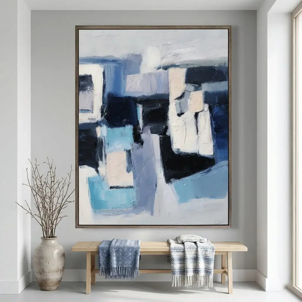 Abstract painting on a wall above a wooden bench with striped blankets in a room.
