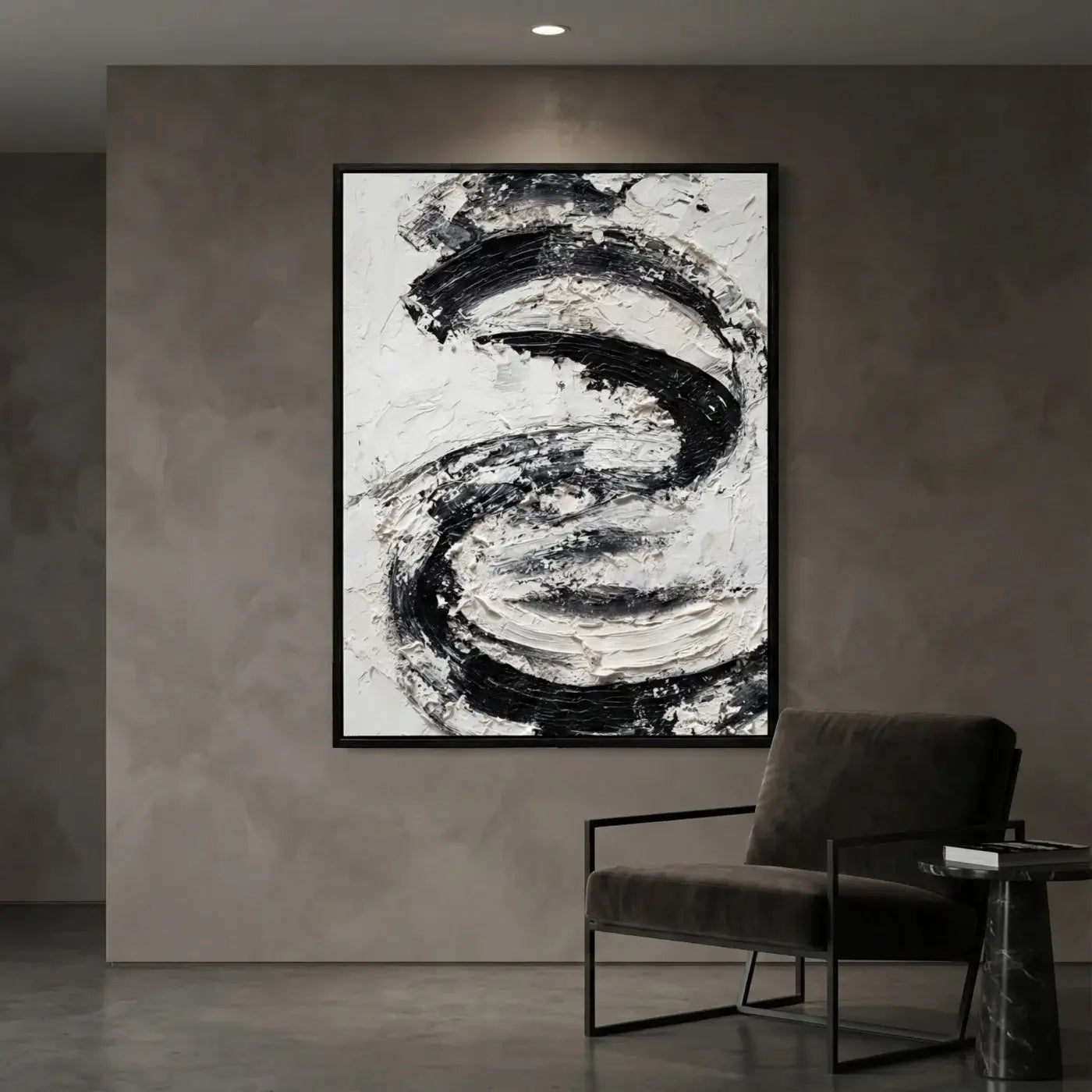 Abstract black and white painting on a textured wall with a chair and table in the foreground.