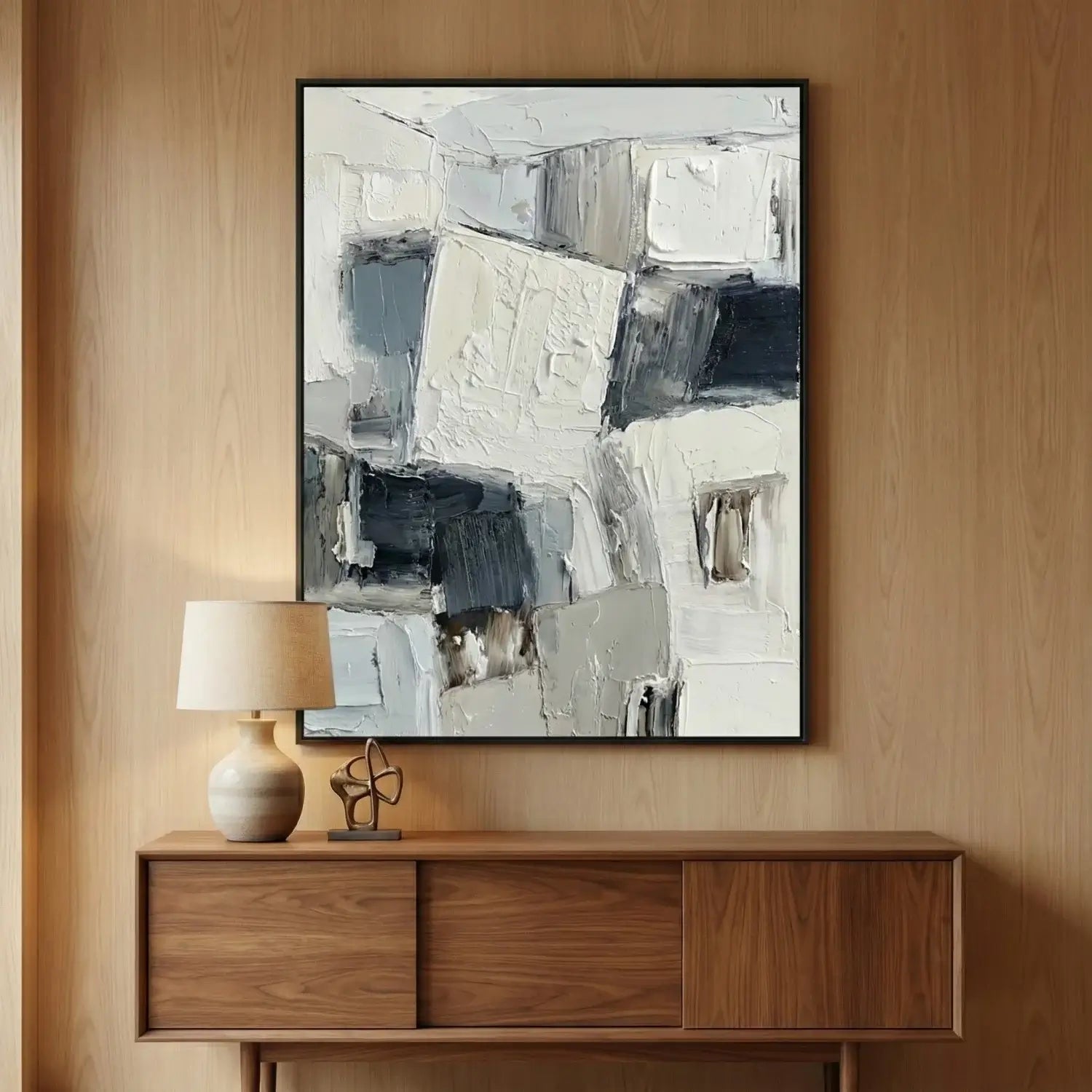 Abstract painting on a wall above a wooden console table with a lamp and decorative object.