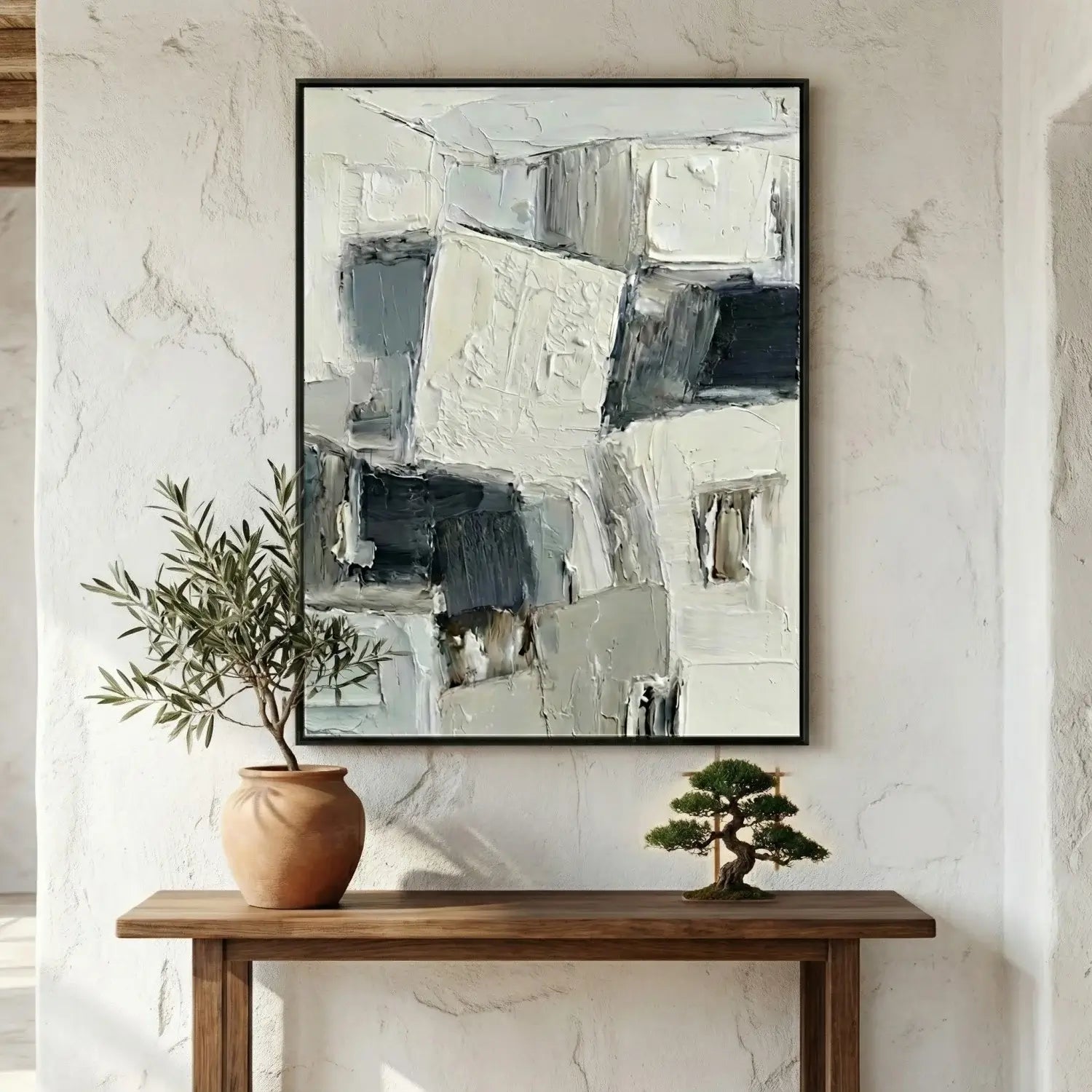Abstract painting on a wall above a wooden console table with decorative plants.