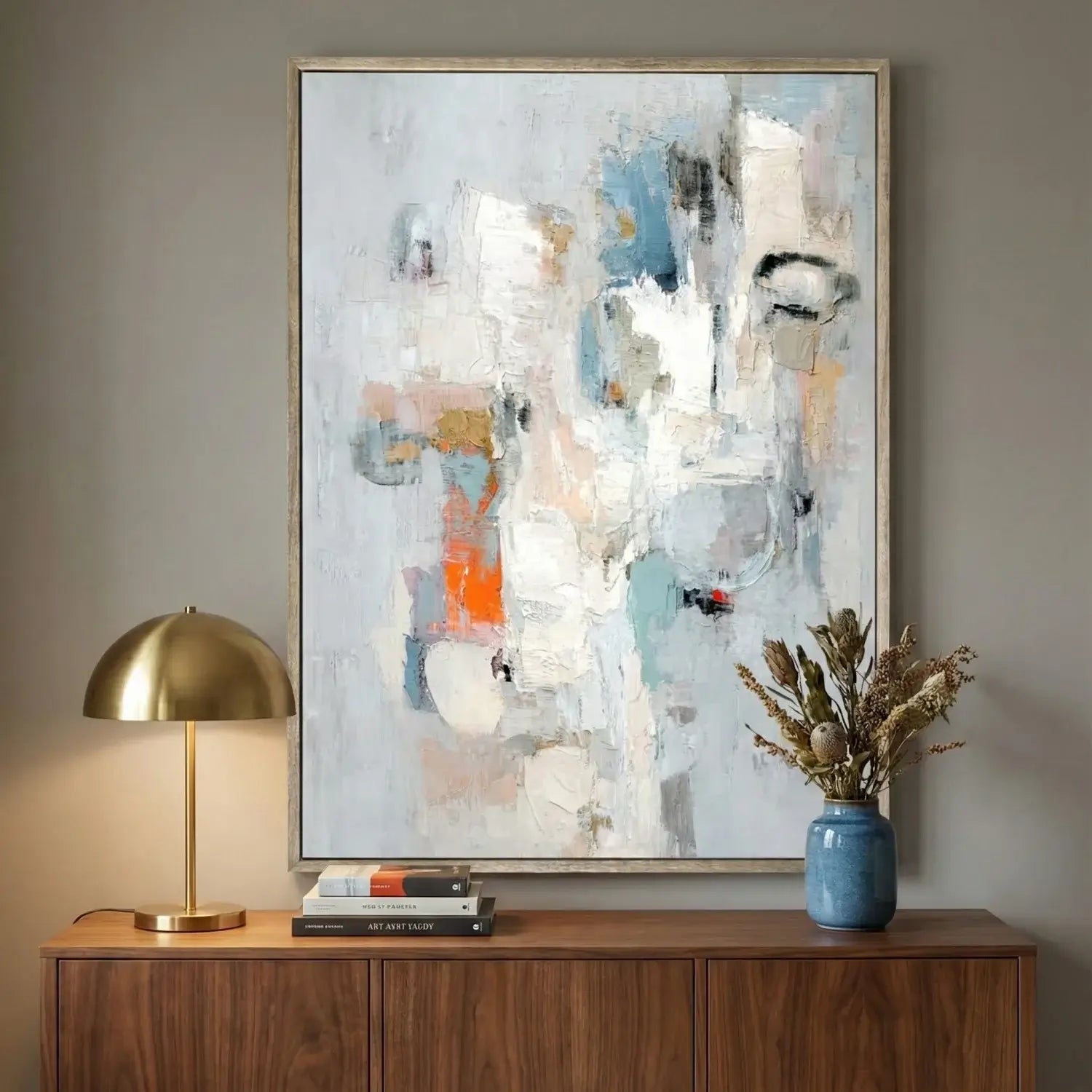 Abstract painting on a wall above a wooden console table with decorative items.