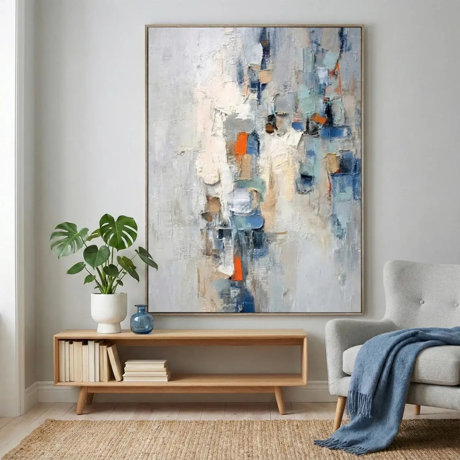 Living room with abstract art, plant, and books on a shelf.