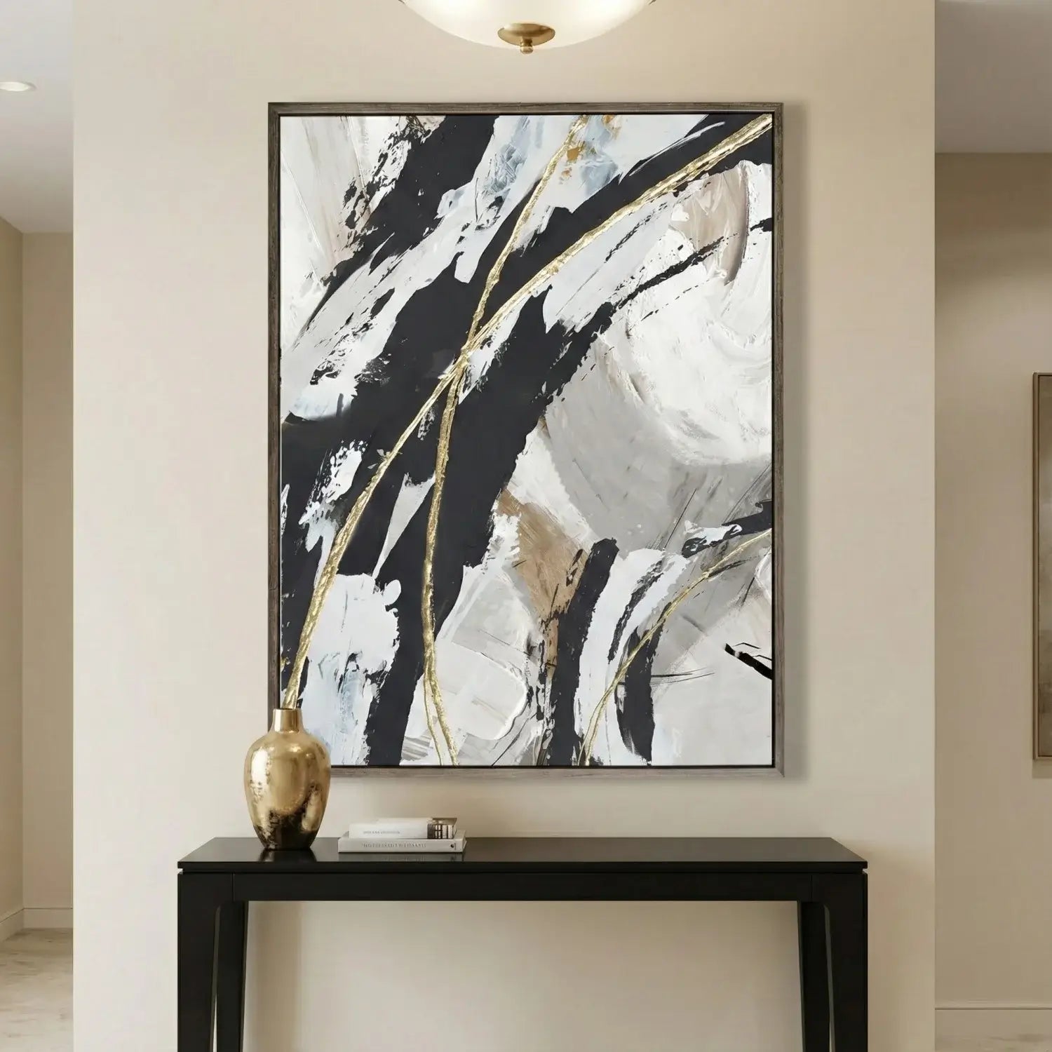 Abstract art piece with black, white, and gold on a wall above a console table.