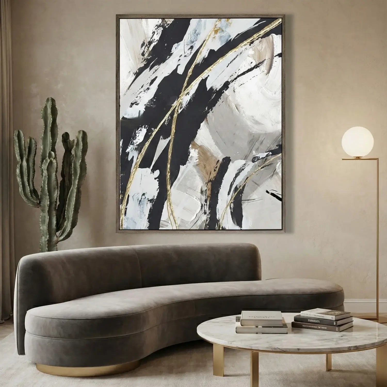 Modern living room with a curved gray sofa, abstract painting, cactus plant, and round table.