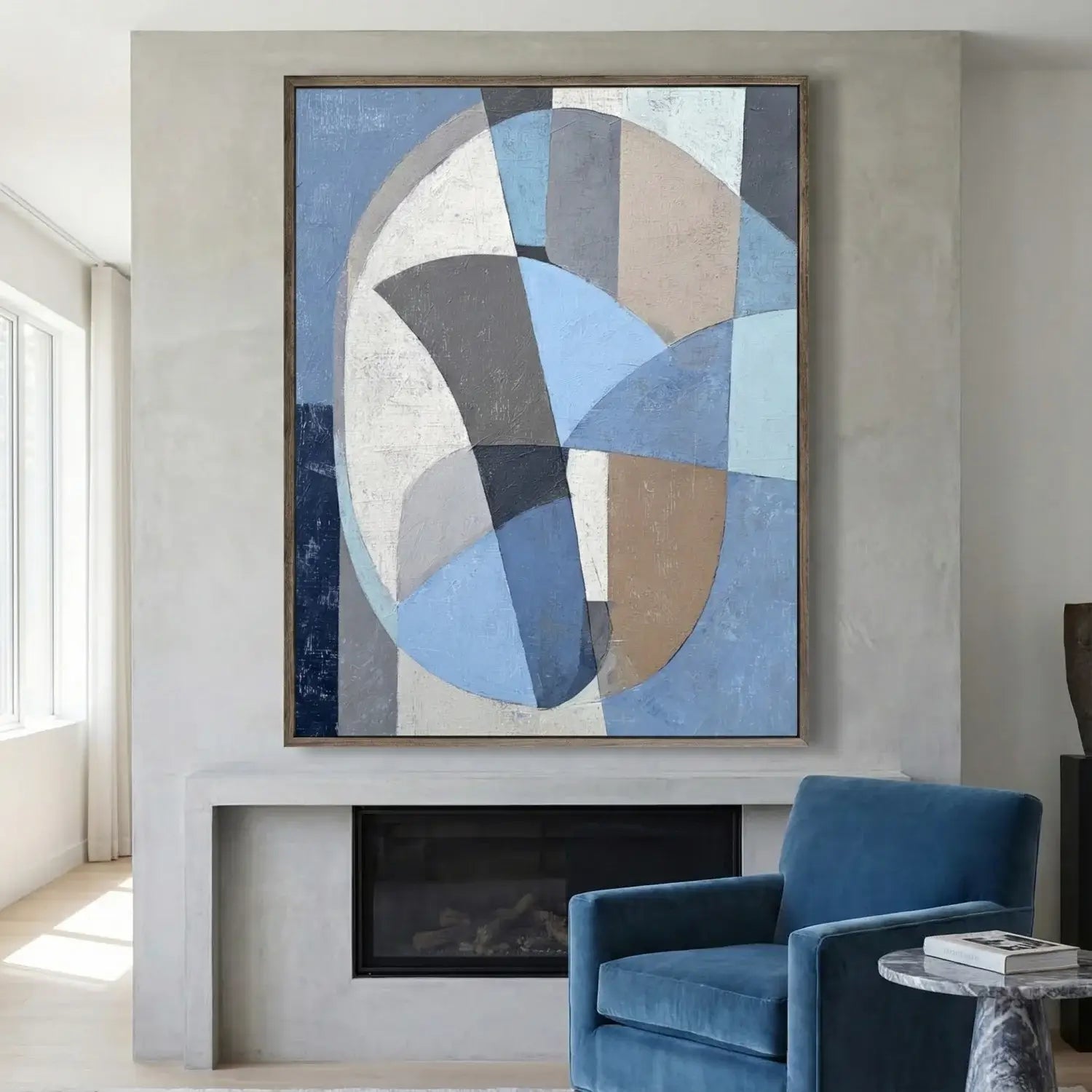 Abstract art piece on a wall above a fireplace with a blue armchair in the foreground.