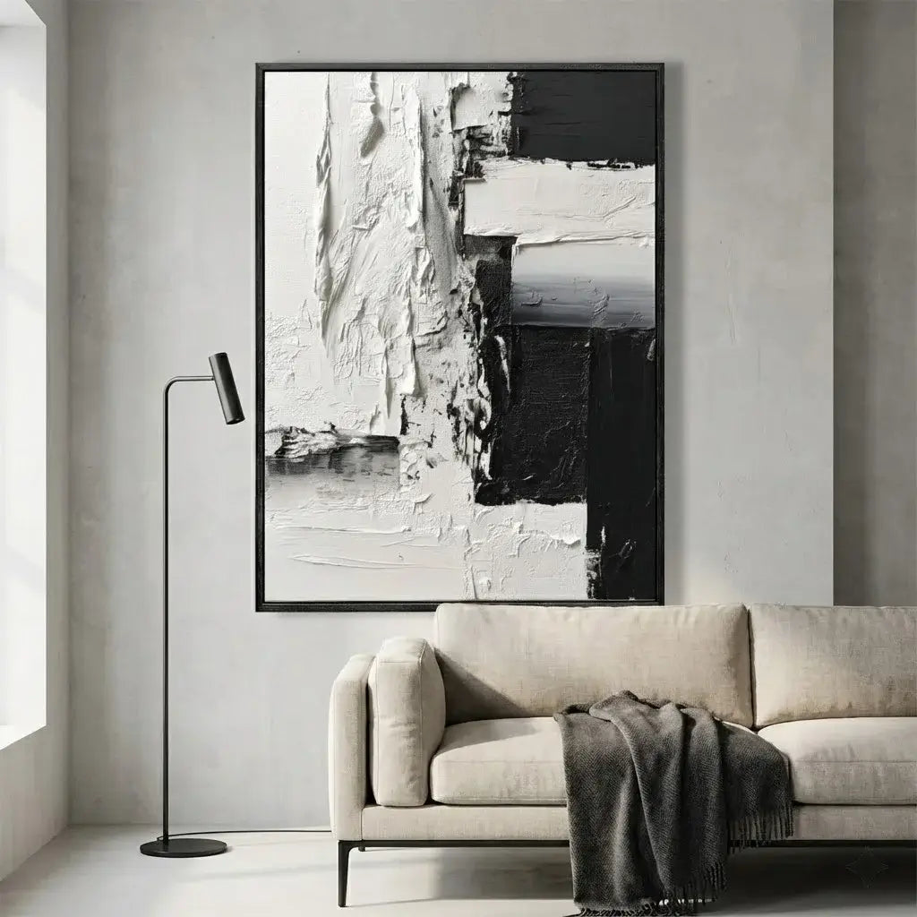 Abstract black and white painting in a modern living room with a beige sofa and floor lamp.