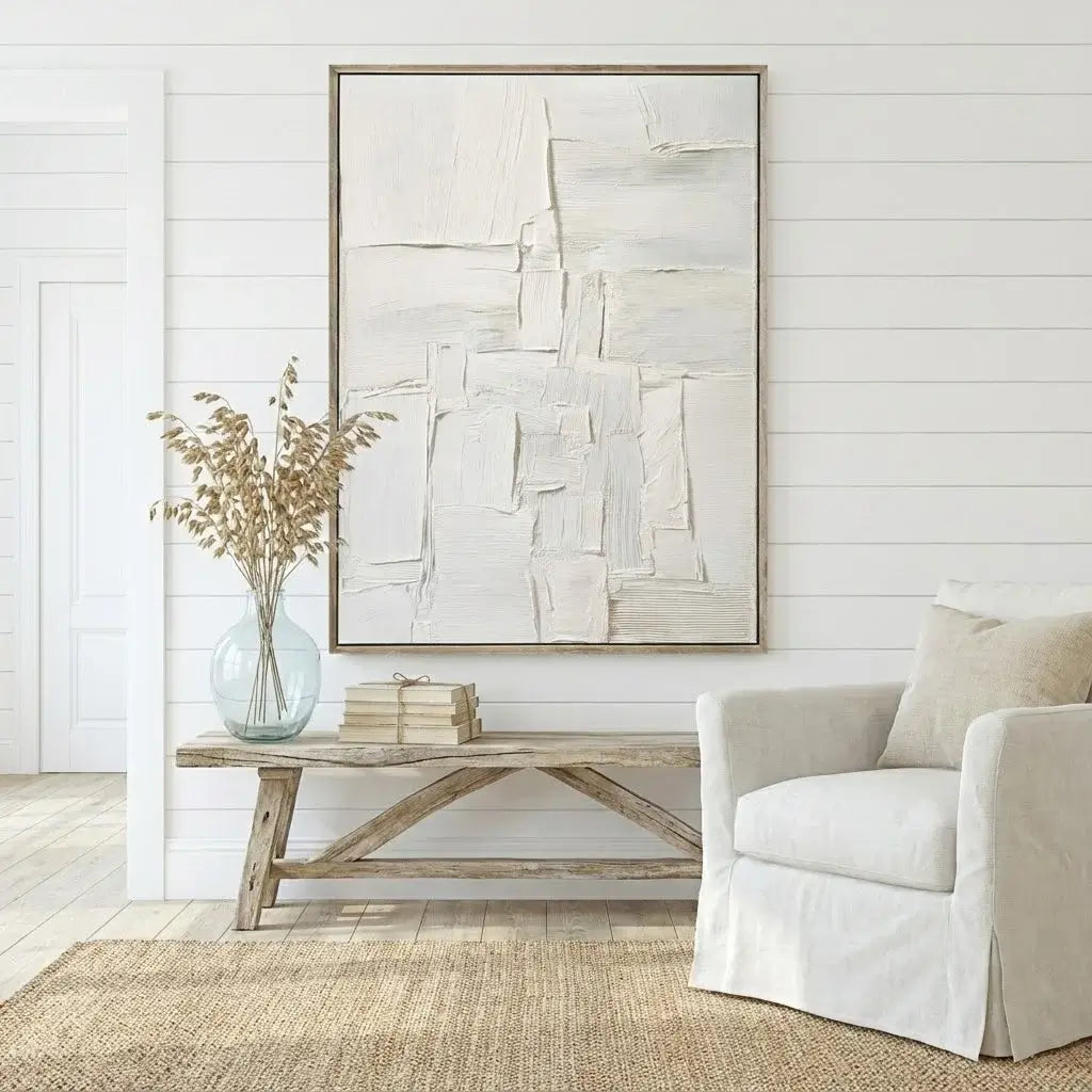 Living room with abstract art, vase with dried flowers, and white armchair.