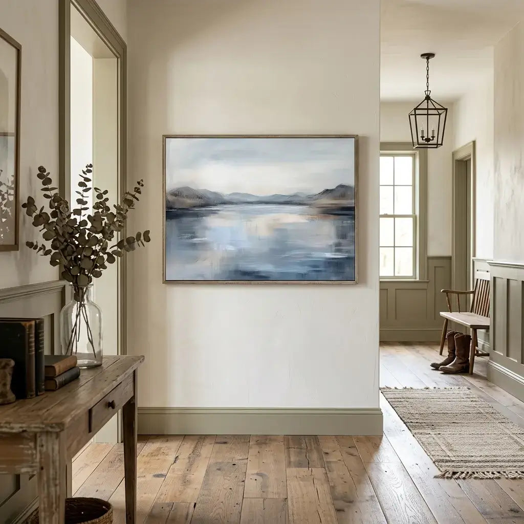 Foyer with a painting of a landscape on the wall, wooden floor, and bench.