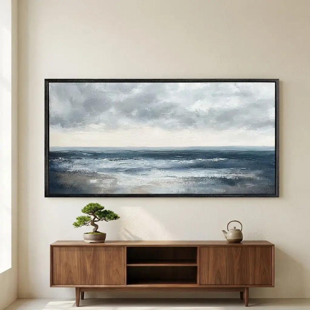 Framed artwork of a seascape above a wooden cabinet with decorative items.