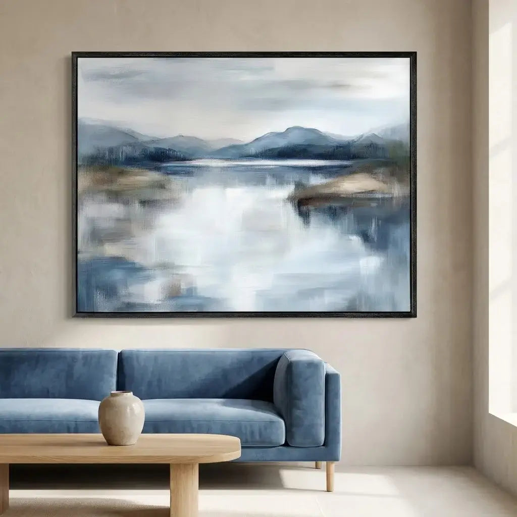 Framed abstract landscape painting above a blue sofa in a room with natural light.