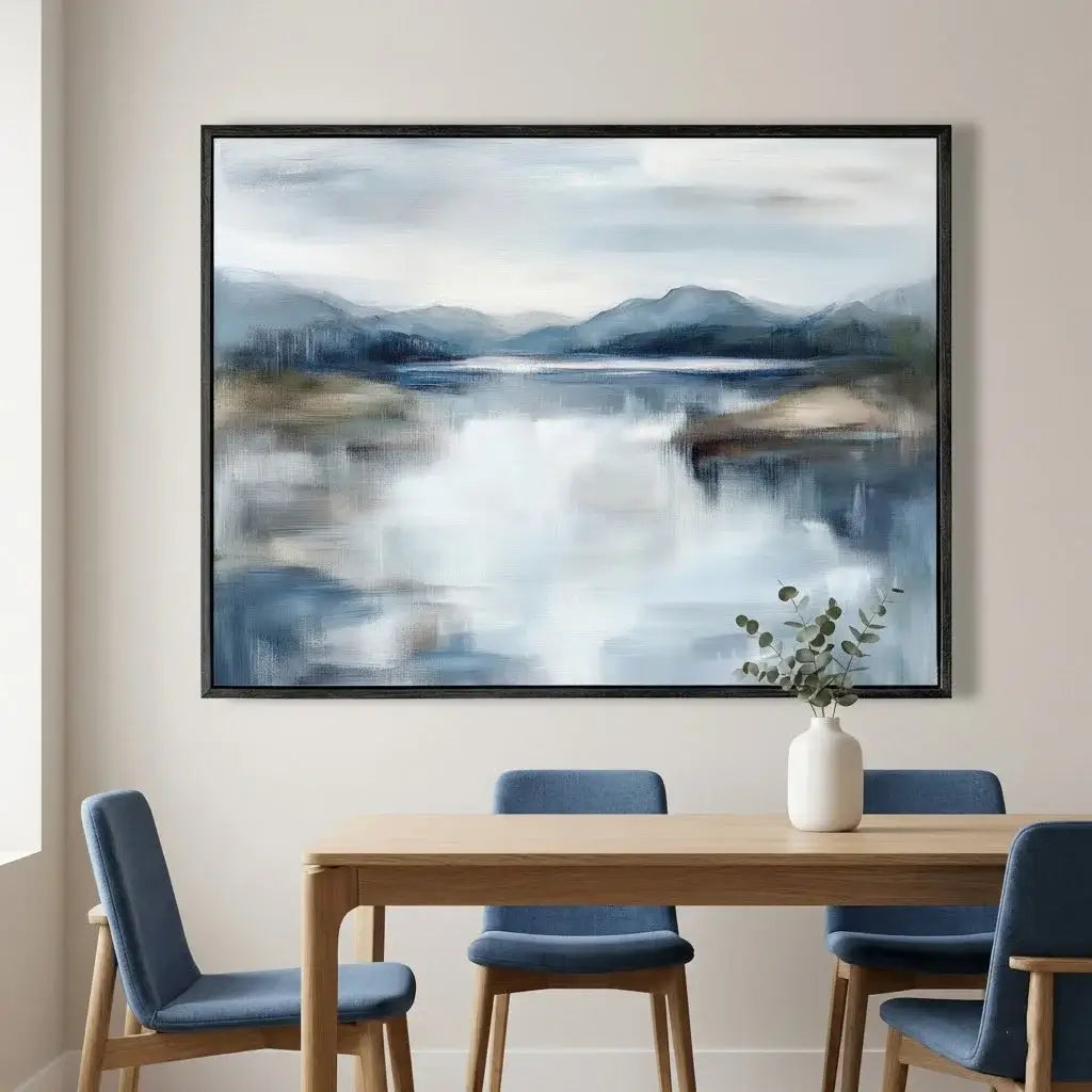Framed landscape painting above a dining table with chairs in a room setting.