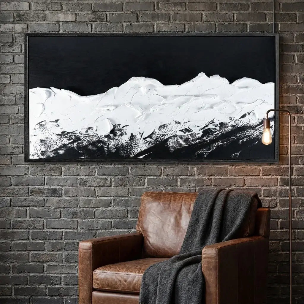 Framed landscape artwork on a brick wall above a brown leather chair.
