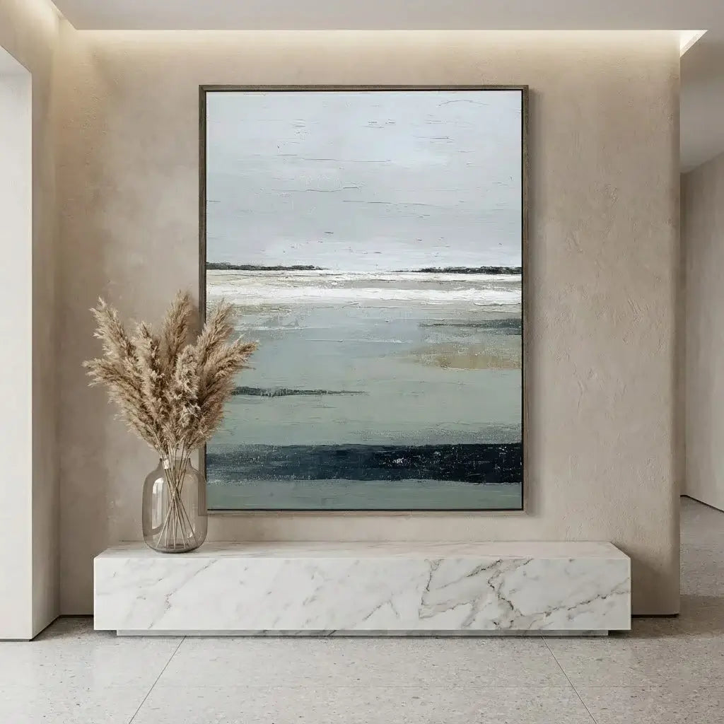 Abstract painting on a wall above a marble console table with a vase of dried plants.