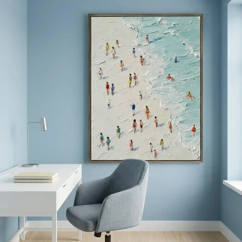 Framed artwork of a beach scene with people on a blue wall above a desk.